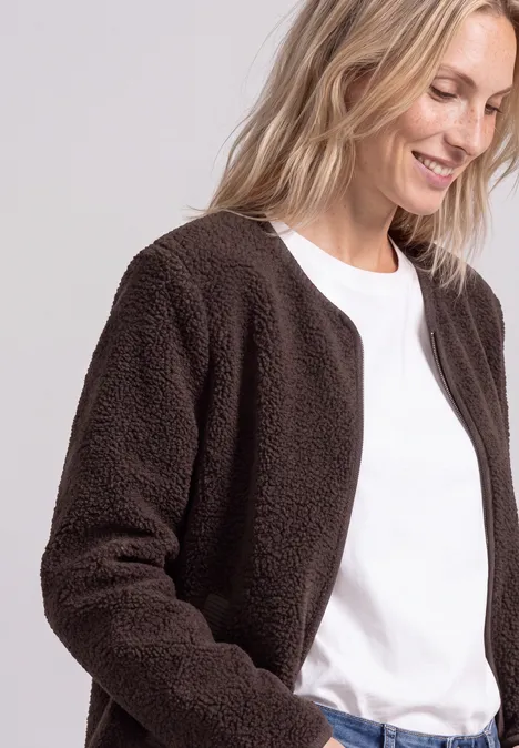 Lächelnde Frau in weißem T-Shirt und brauner Teddyjacke.