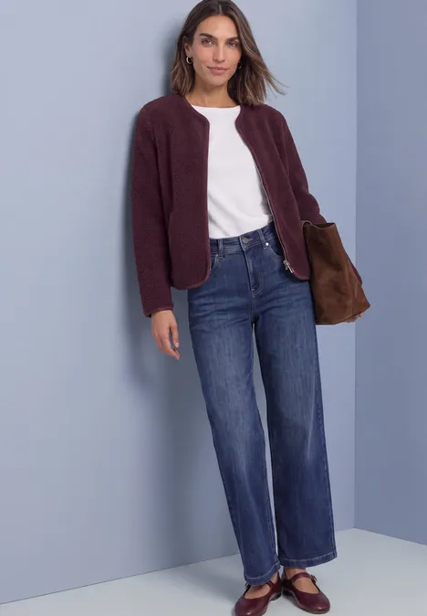 Teddy-Jacke mit Rundhals und Corddetails rustic rouge Frau in weißem T-Shirt, weinroter Jacke, weitem Jeans und Ballerinas mit brauner Tasche.