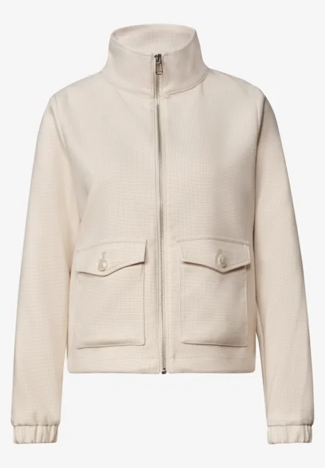 Veste polaire beige à col montant, fermeture éclair et poches plaquées.