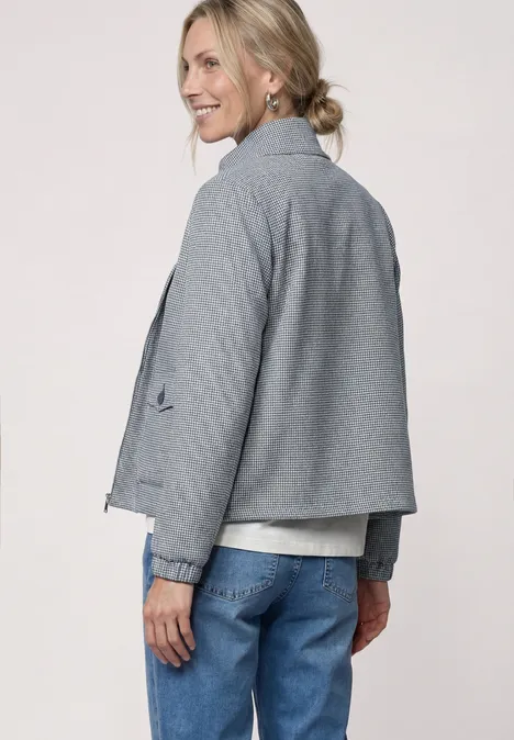 Vue de dos d'une personne en veste grise, jean bleu et chignon décontracté.