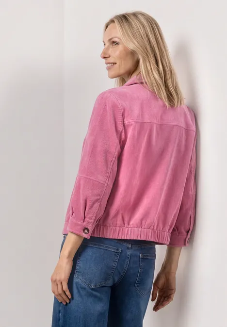 3/4 Arm Cordjacke mit Hemdkragen blush berry Frau von hinten in rosa Jacke und blauen Jeans vor neutralem Hintergrund.