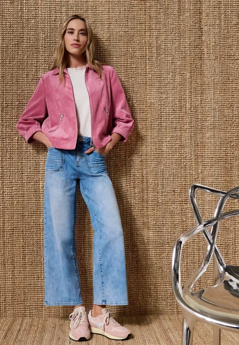 3/4 Arm Cordjacke mit Hemdkragen blush berry Person in rosa Jacke, weißem Top, weiten Jeans und rosa Sneakers vor strukturiertem Hintergrund.