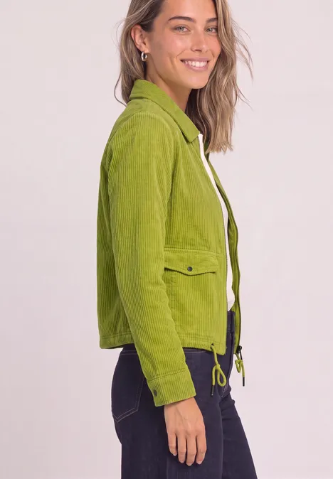 Frau trägt smaragdgrüne Jacke mit Klappentaschen und Kordelzug, lächelnd vor hellem Hintergrund.