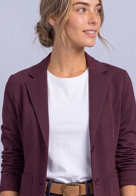 Eenvoudige blazer in effen kleur rustic rouge Vrouw met wit T-shirt en donkerpaarse blazer, kijkt iets naar rechts.