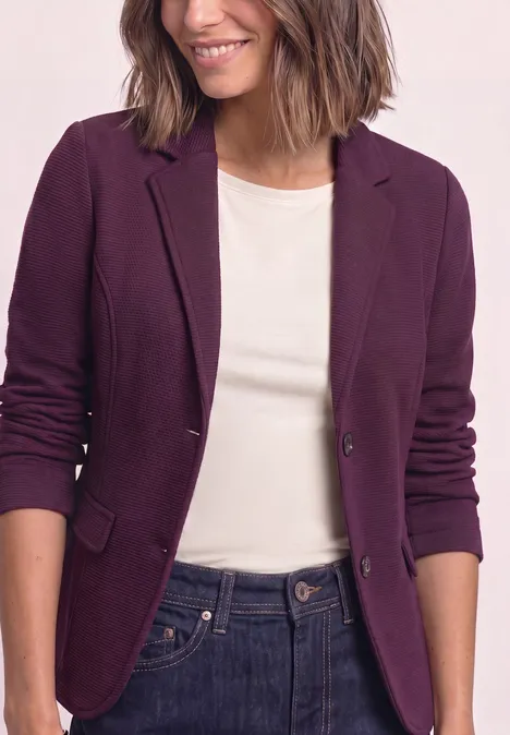 Frau trägt lila Blazer über weißem T-Shirt und Jeans