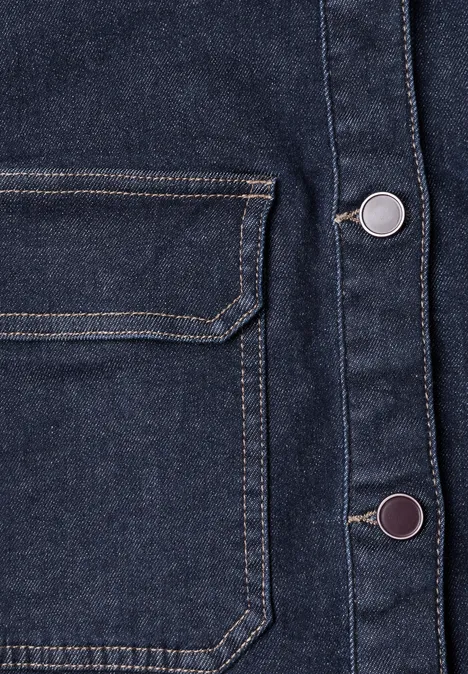 Gros plan d’une veste en jean foncé avec poche avant et boutons-pression métalliques.
