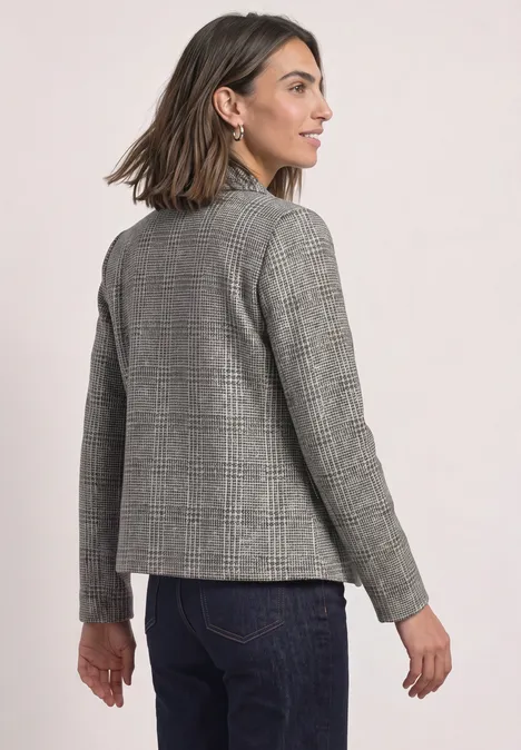Blazer à carreaux et boutons Black Frau trägt grauen Karoblazer und Jeans, blickt seitlich nach links.