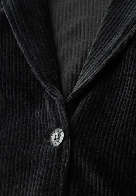 Nahaufnahme eines schwarzen Cord-Blazers mit Knopf und Revers, feine vertikale Struktur sichtbar.