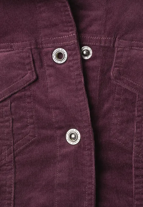 Lila Cordjacke mit silbernen Druckknöpfen und aufgesetzten Taschen im Detail.