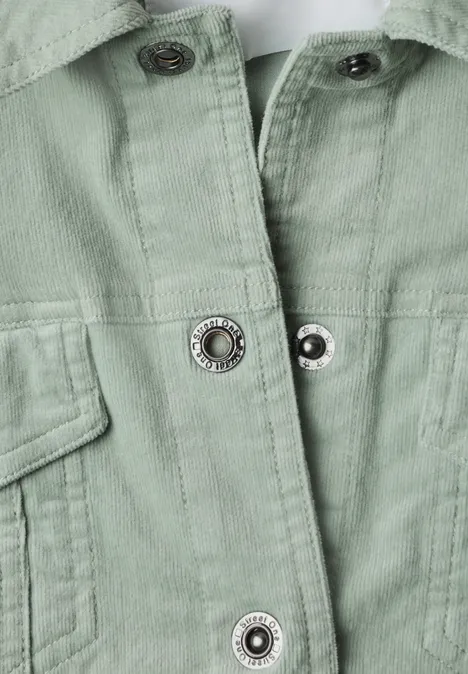 Gros plan d'une veste vert pâle avec boutons-pression et poches plaquées.