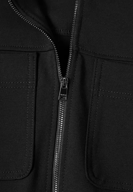 Close-up van een zwart jack met centrale ritssluiting en opgestikte zakken.