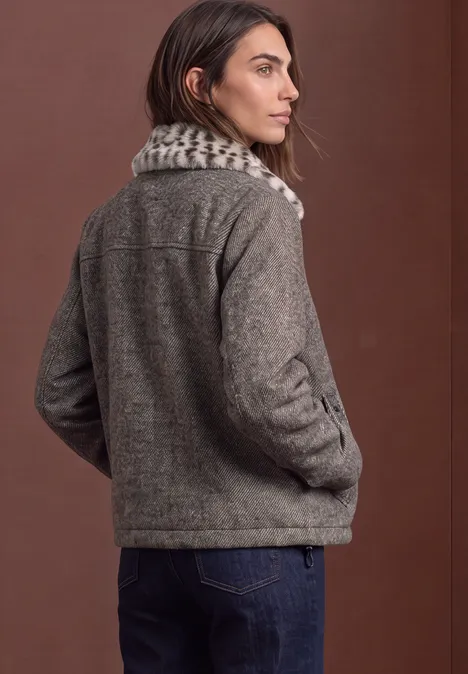 Eine Frau trägt eine graue Wolljacke mit Kunstfellkragen.