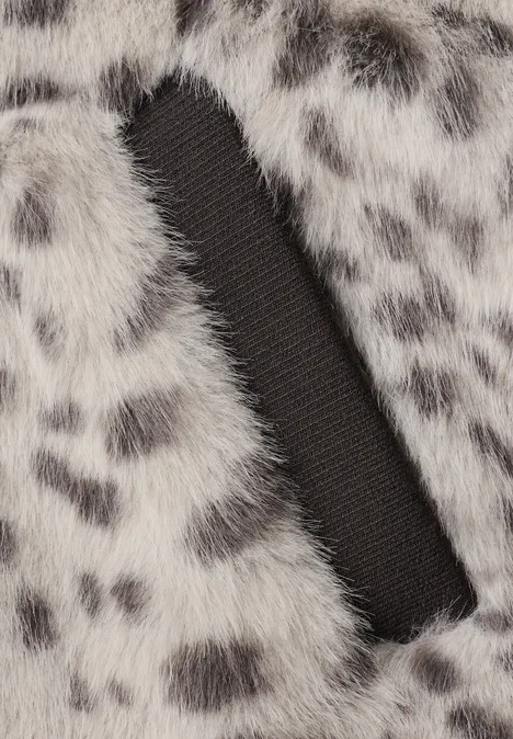Nahaufnahme von flauschigem, grau-weißem Kunstpelz mit schwarzen Flecken und einem schwarzen Stoffdetail.