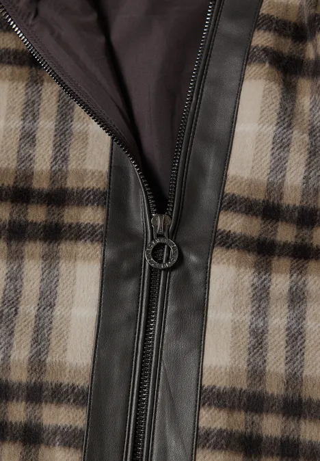 Nahaufnahme einer karierten Jacke mit Lederbesatz und Metallreißverschluss.