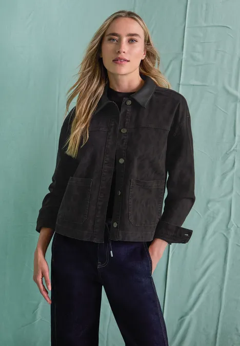 Jeansjacke mit Leo-Muster und Kragen Leo Print Washed Eine blonde Frau trägt vor grünem Hintergrund eine dunkelgraue Cordjacke und dunkle Hose.