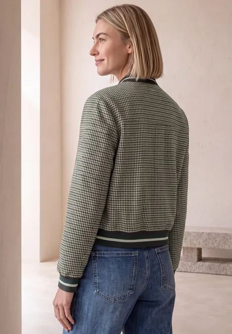 Blouson mit Zipper und Karomuster sanded amber Eine Frau mit kurzen blonden Haaren trägt eine grün gestreifte Bomberjacke und Jeans und steht seitlich.