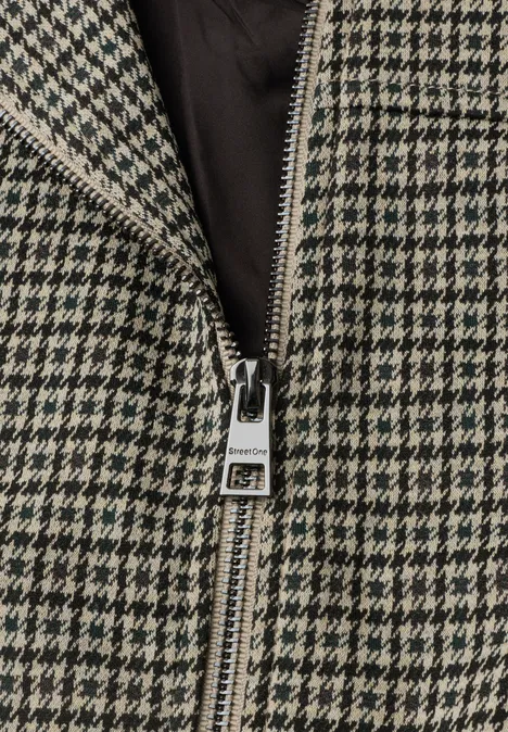 Blouson mit Zipper und Karomuster sanded amber Nahaufnahme eines Reißverschlusses an einem schwarz-weißen Hahnentritt-Mantel.