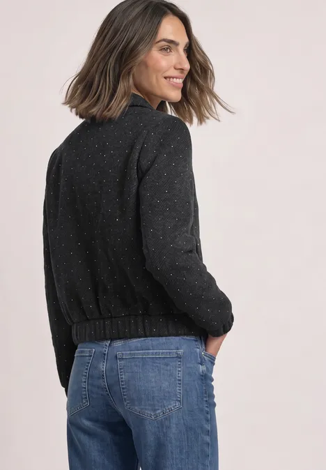 Frau in dunklem Pullover und Jeans blickt lächelnd über die Schulter.