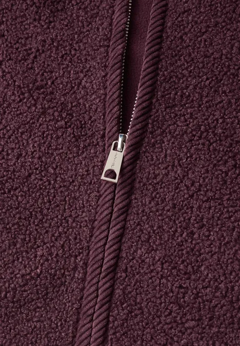 Close-up van bordeaux fleece-stof met een centrale rits.