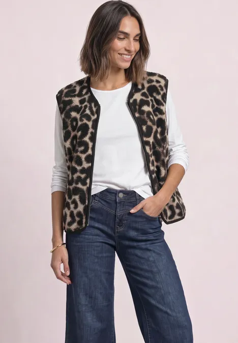 Gilet en peluche à fermeture zip et détails en velours côtelé Black Frau in weißem Top und Jeans trägt ärmellose Weste mit Leopardenmuster und lächelt