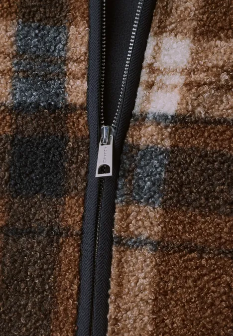 Gilet en peluche à fermeture zip et détails en velours côtelé Obsidian Blue Nahaufnahme eines Reißverschlusses an kariertem braunem Fleece mit schwarzem Reißverschlussband