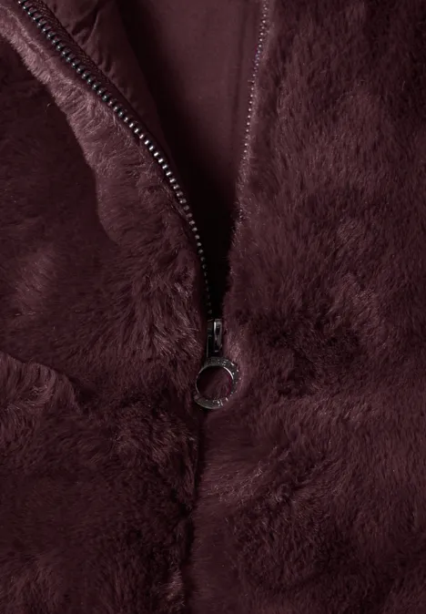 Detail van een bordeauxrode pluche stof met rits en ringtrekker.