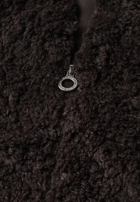 Nabijopname van donkerbruin teddyfleece met zilverkleurige ritstrekker.