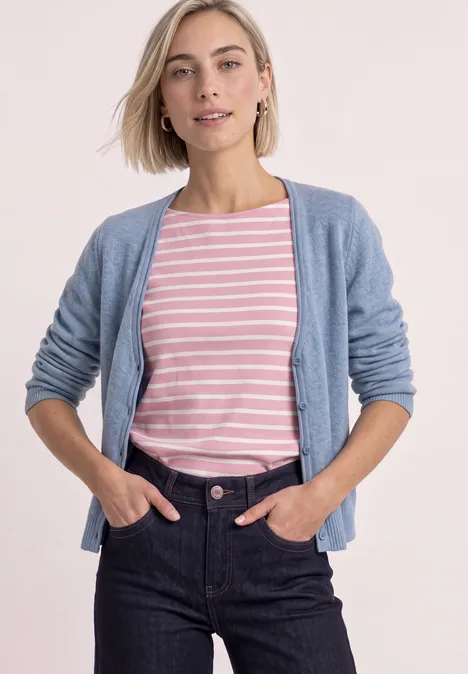 Frau in rosa-weiß gestreiftem T-Shirt, hellblauer Strickjacke und dunklen Jeans.