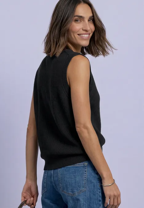 Strickweste mit Rundhals und Knopfleiste Black Frau mit dunklen Haaren in schwarzem ärmellosem Oberteil und Jeans blickt lachend über die Schulter.
