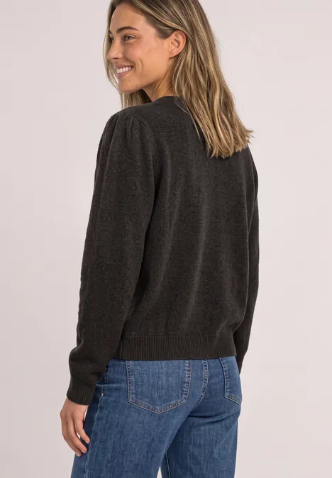 Langarm Cardigan mit Rundhals und Knöpfen black coffee mel. Eine Frau in schwarzem Pullover und blauer Jeans lächelt seitlich zur Kamera, mit Blick über die Schulter.