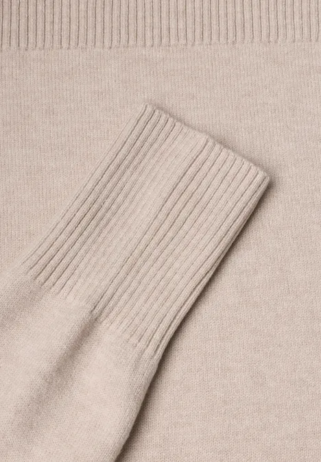 Gros plan sur un pull en maille beige avec manche étendue