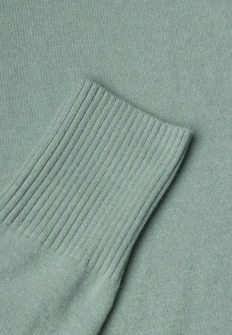 Ein mintgrüner Strickpullover mit geripptem Ärmelbündchen.