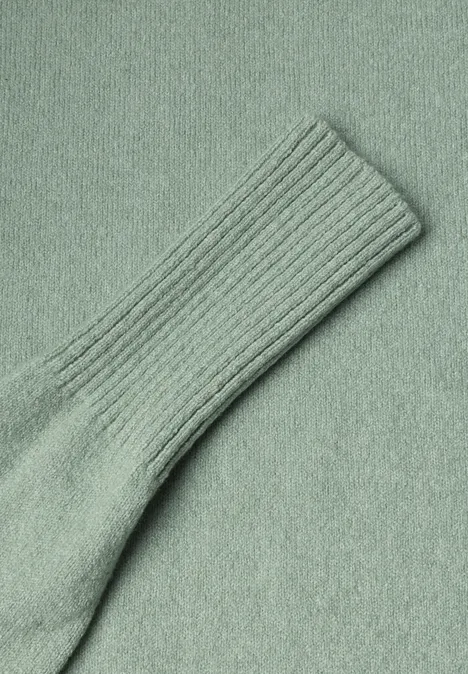 Nahaufnahme einer hellgrünen, gerippten Stricksocke aus weichem Stoff.