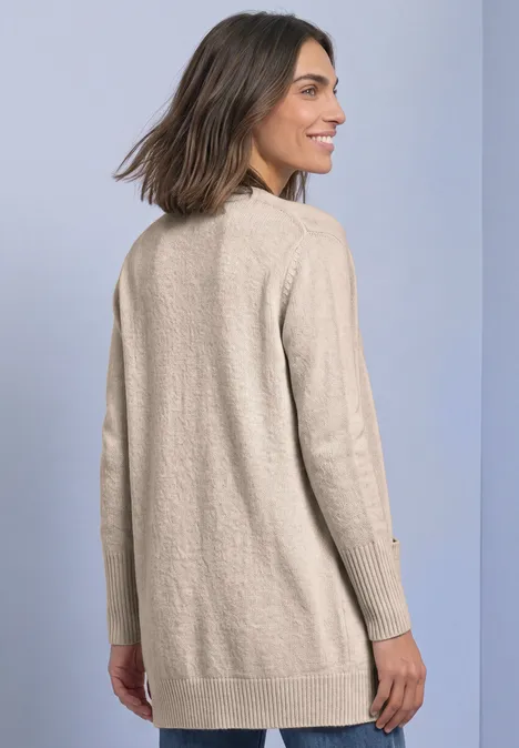 Langarm Cardigan mit aufgesetzten Taschen clay sand mel. Frau mit schulterlangem braunem Haar von hinten, trägt langen beigen Cardigan und lächelt leicht.