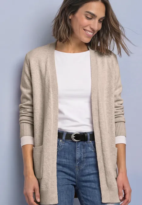 Langarm Cardigan mit aufgesetzten Taschen clay sand mel. Frau in hellbeiger Strickjacke, weißem T-Shirt und Jeans vor neutralem Hintergrund