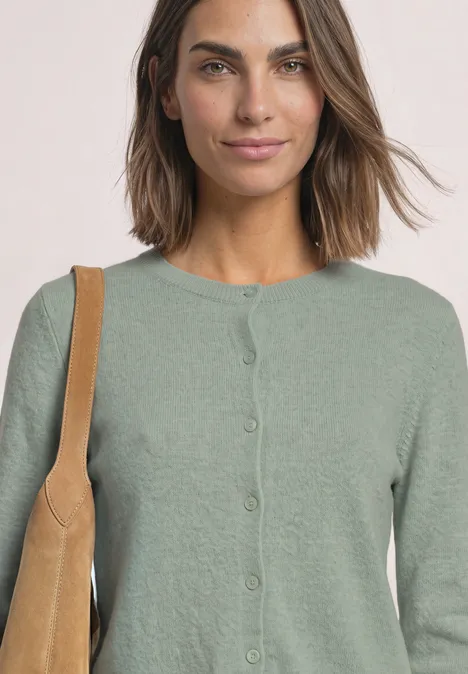 Cardigan mit Rundhals und Rüschendetails eucalyptus green mel. Frau in grünem Cardigan mit Schultertasche vor hellem Hintergrund.