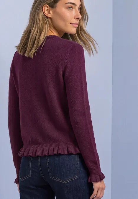 Cardigan mit Rundhals und Rüschendetails berry maroon Frau in seitlicher Rückenansicht trägt violetten Pullover mit Rüschensaum und dunkelblaue Jeans vor hellem Hintergrund.