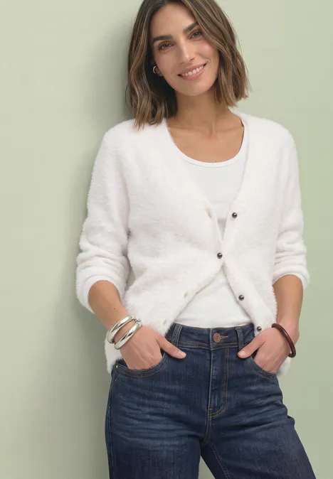 Cardigan à manches longues, col en V et boutons off white Frau in weißem Cardigan und Jeans vor hellem Hintergrund lächelnd