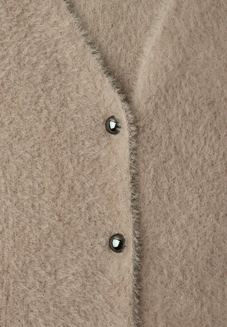 Beige, pluizige gebreide cardigan met twee donkere knopen, zacht materiaal.