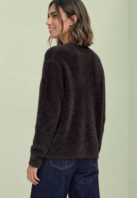 Langarm Cardigan mit V-Neck und Knöpfen black coffee Frau in schwarzem, flauschigem Pullover und blauen Jeans, seitlich von hinten fotografiert.