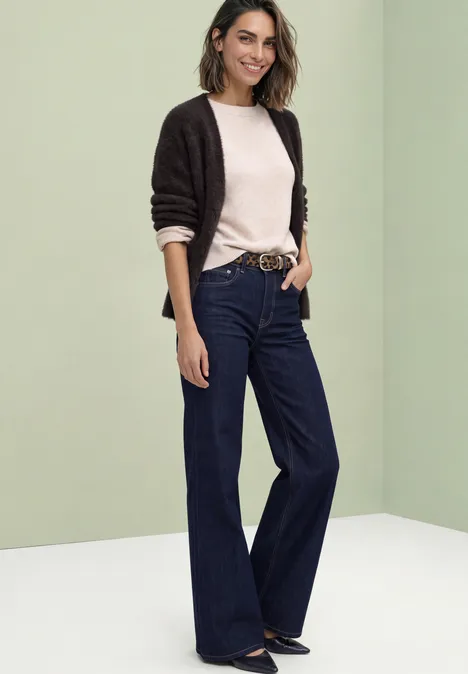 Langarm Cardigan mit V-Neck und Knöpfen black coffee Eine Frau in weitem dunkelblauen Jeans, hellem Pullover und schwarzer Strickjacke vor grünlich-weißer Kulisse.