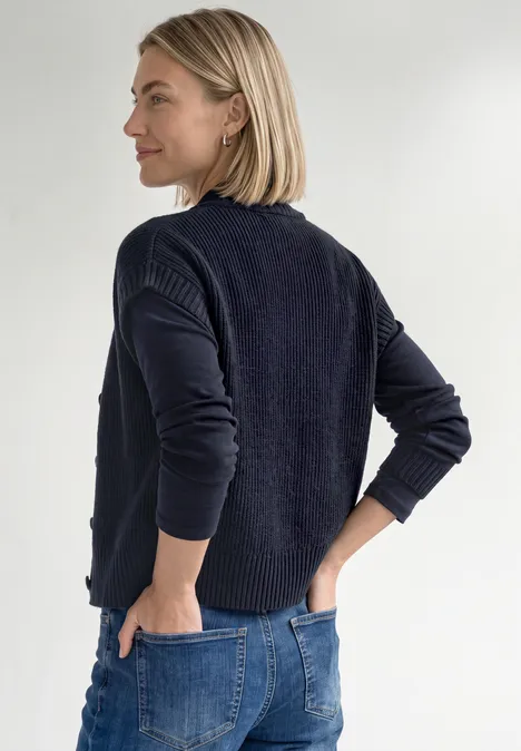 Vest met afhangende schouders, coltrui en ritssluiting indigo night mel. Frau mit kurzem blondem Haar trägt dunkelblauen Pullover und Jeans, steht seitlich mit Händen an den Hüften.