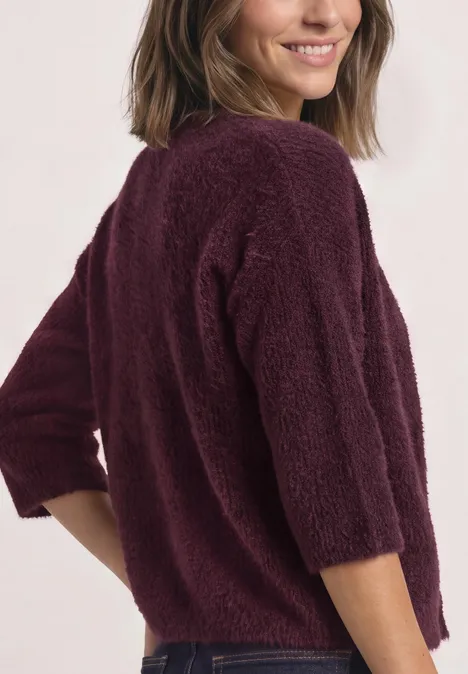 Frau von hinten in flauschigem, bordeauxrotem Pullover mit 3/4-Ärmeln.