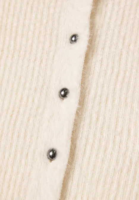 Beiges geripptes Strickstück mit drei schwarzen Knöpfen.