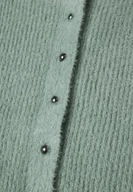 Flauschiger, salbeigrüner Strickstoff mit senkrechter Reihe silberner Druckknöpfe.