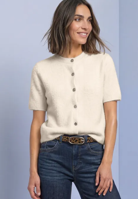 Femme en gilet tricoté crème à manches courtes boutonné, jean et ceinture
