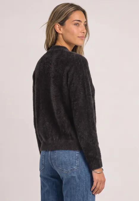 Cardigan en laine fine avec fermeture éclair black coffee Frau von hinten mit schwarzem, flauschigem Pullover und blauen Jeans vor hellem Hintergrund.