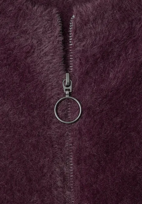 Nahaufnahme eines lila/plumfarbenen Pelzstoffs mit einem Reißverschluss und rundem Ring als Zipper.