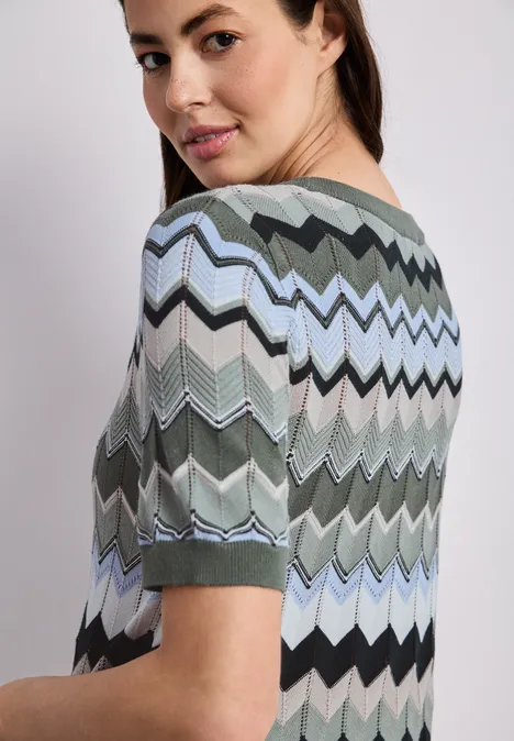 Persoon van achteren in een meerkleurig zigzagshirt met korte mouwen.