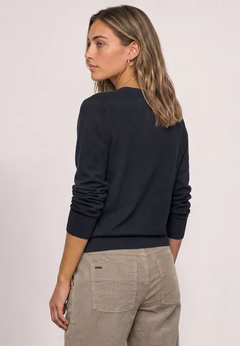 Achteraanzicht van een vrouw in een donkerblauwe trui en beige broek.